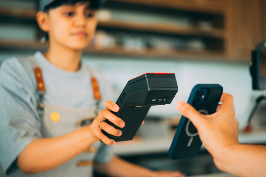 A vendor processing a contactless card payment with a smartphone and card reader