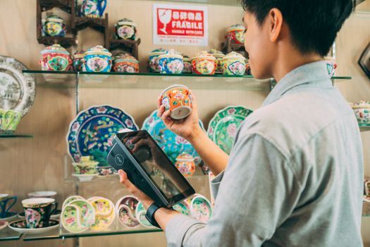 A customer makes a digital payment for colorful ceramic ware at a shop.