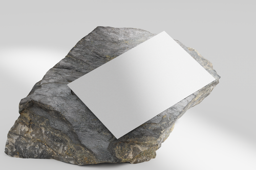 Free A blank paper sheet positioned on a textured rock, ideal for mockup designs. Stock Photo