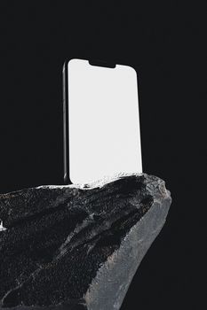 Minimalist smartphone mockup with blank screen on rugged rock for design presentations.