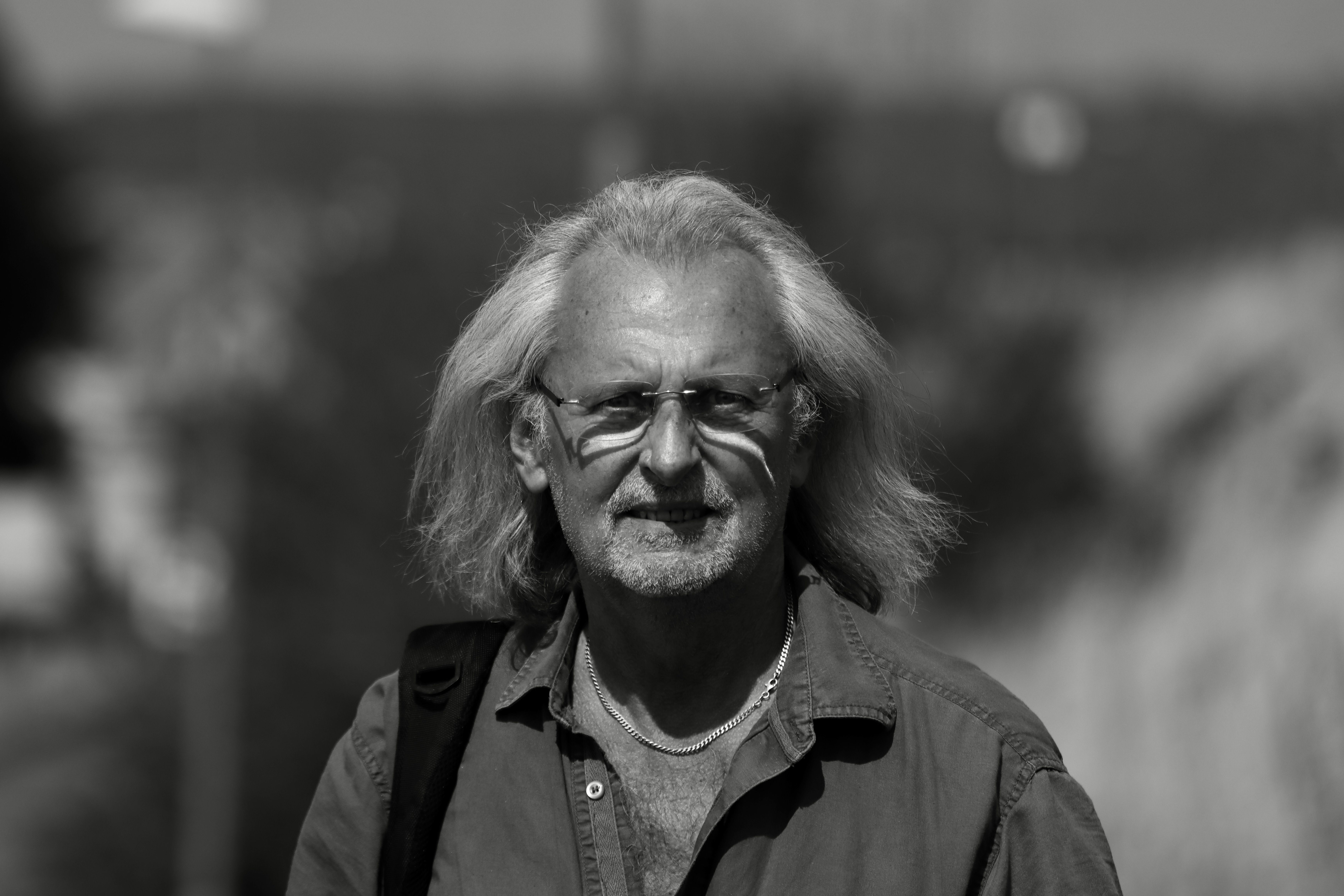 A black and white portrait of an elderly man with eyeglasses and long hair, taken outdoors in Jonkoping, Sweden.