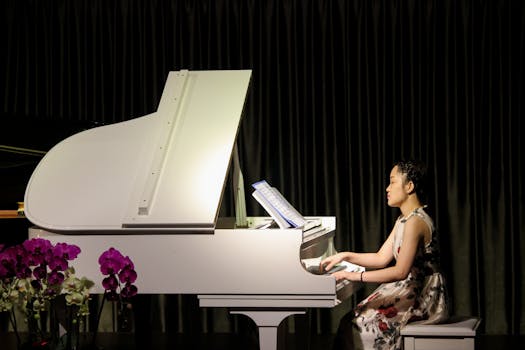 A woman plays a white piano on stage surrounded by flowers, showcasing classical elegance.