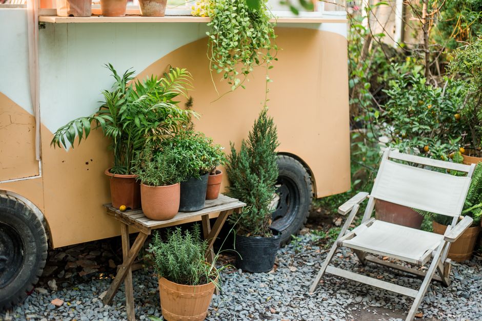 Photo by Vietnam Tri Duong Photographer on Pexels Charming patio space featuring potted plants and a comfortable chair beside a vintage trailer.