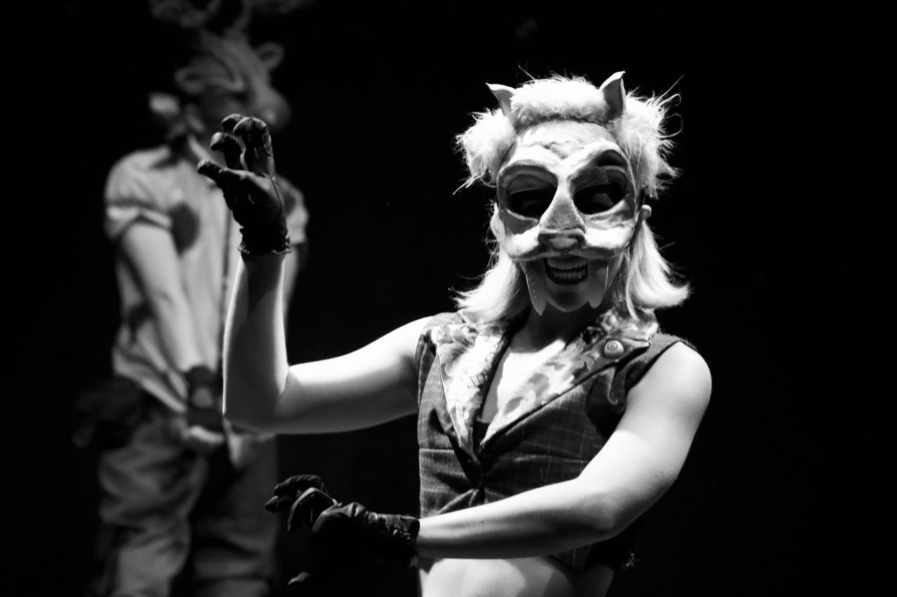a captivating black and white image of actors in animal masks performi