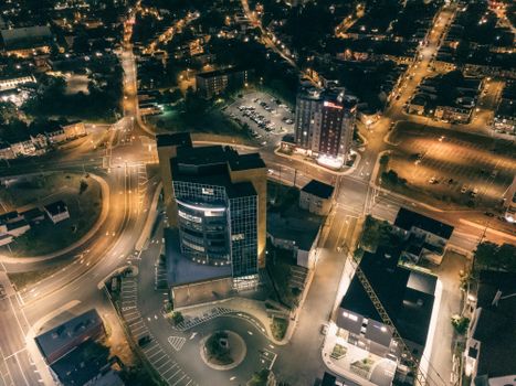 Aerial night photography captures a city's glowing streets and buildings, showcasing urban vibrancy.