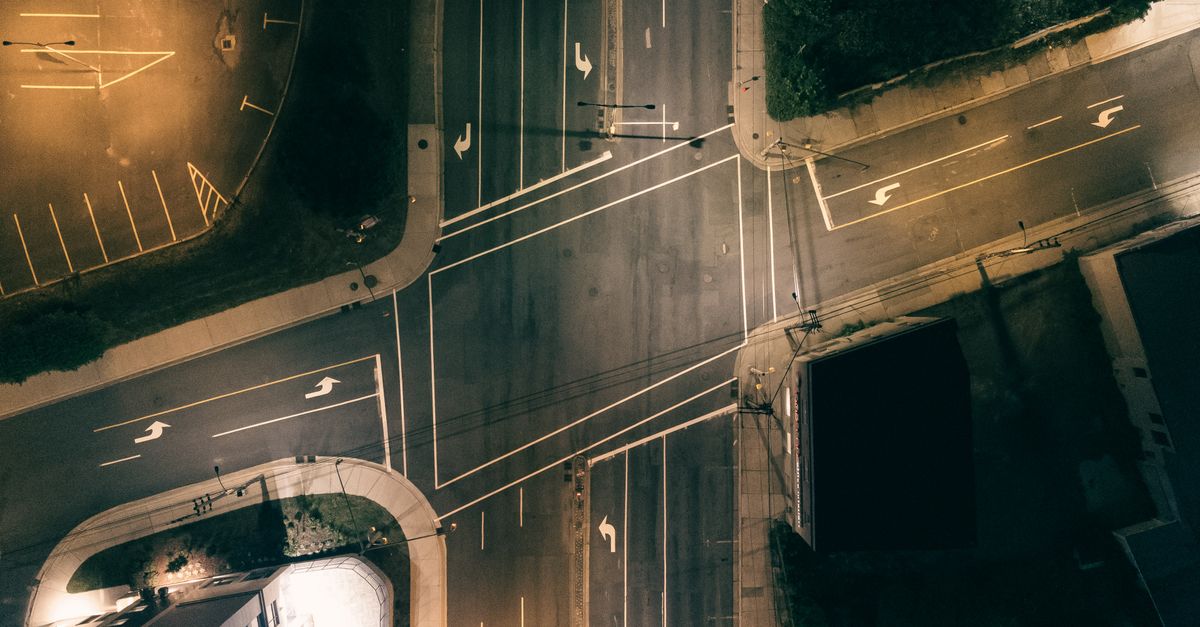 High-angle shot of a deserted city intersection illuminated by street lights at night.