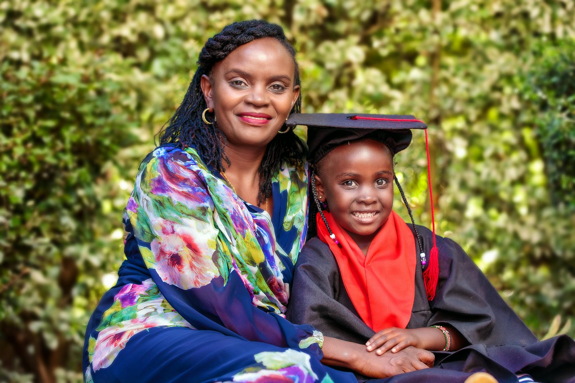 A joyful portrait capturing a mother and daughter celebrating graduation day outdoors.