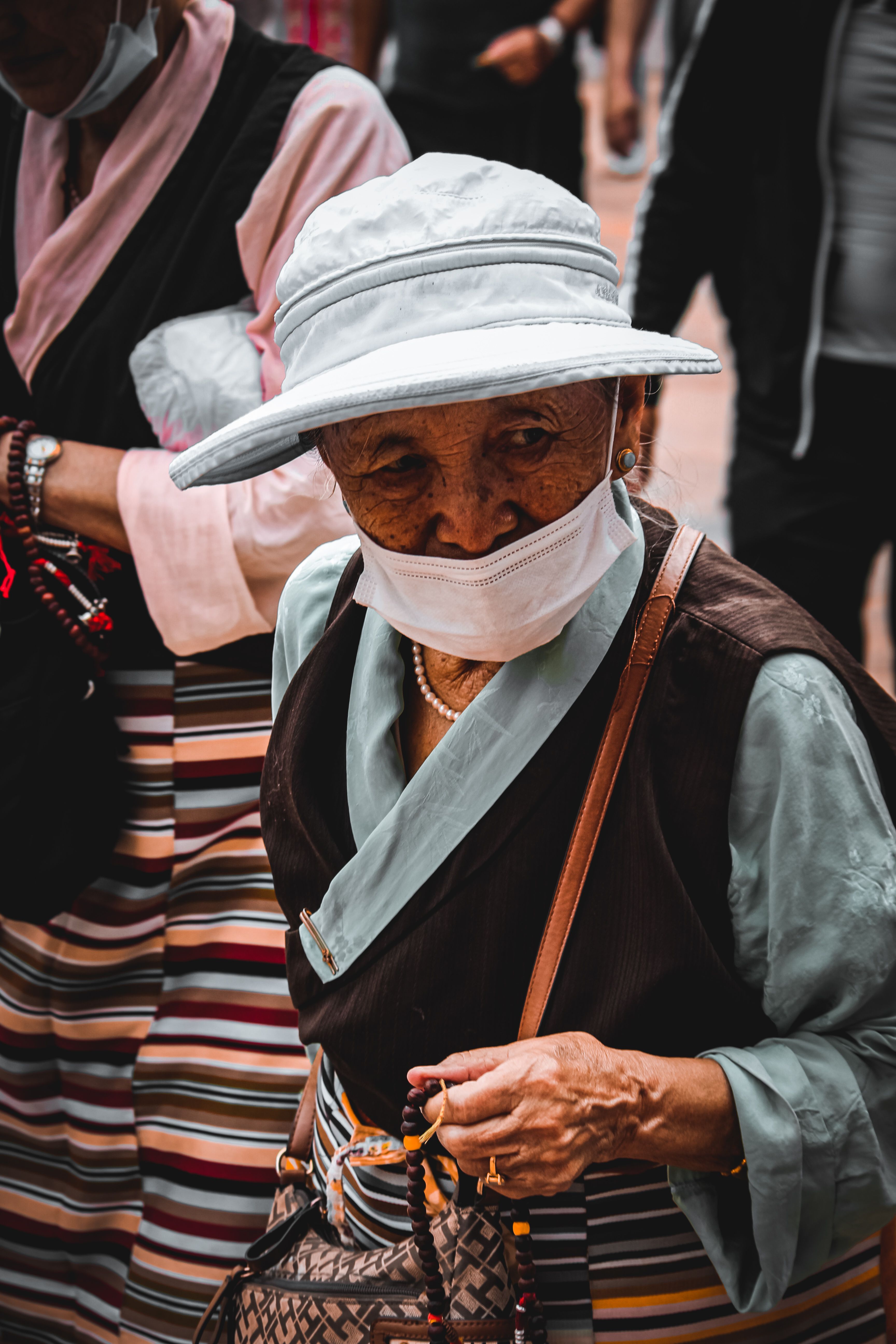 Elderly Woman in Face Mask Holding Prayer Beads · Free Stock Photo