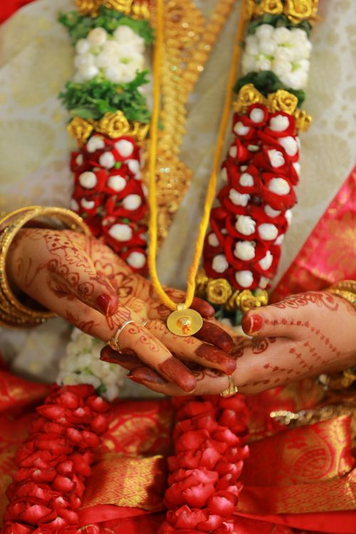 Free Close-up of hands with henna and traditional jewelry in Indian wedding attire, holding a pendant. Stock Photo