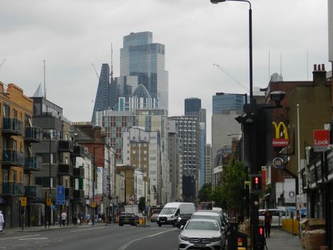 Street view of London's skyline on a cloudy day, featuring modern skyscrapers and bustling city life.