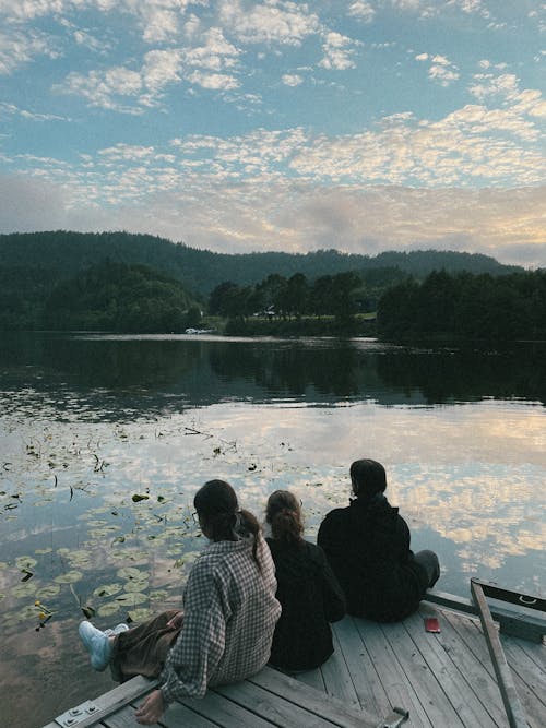 People Sitting on Wooden Dock over the Lake