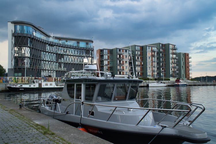 A Boat Docked On The Side Of The River Near City Buildings