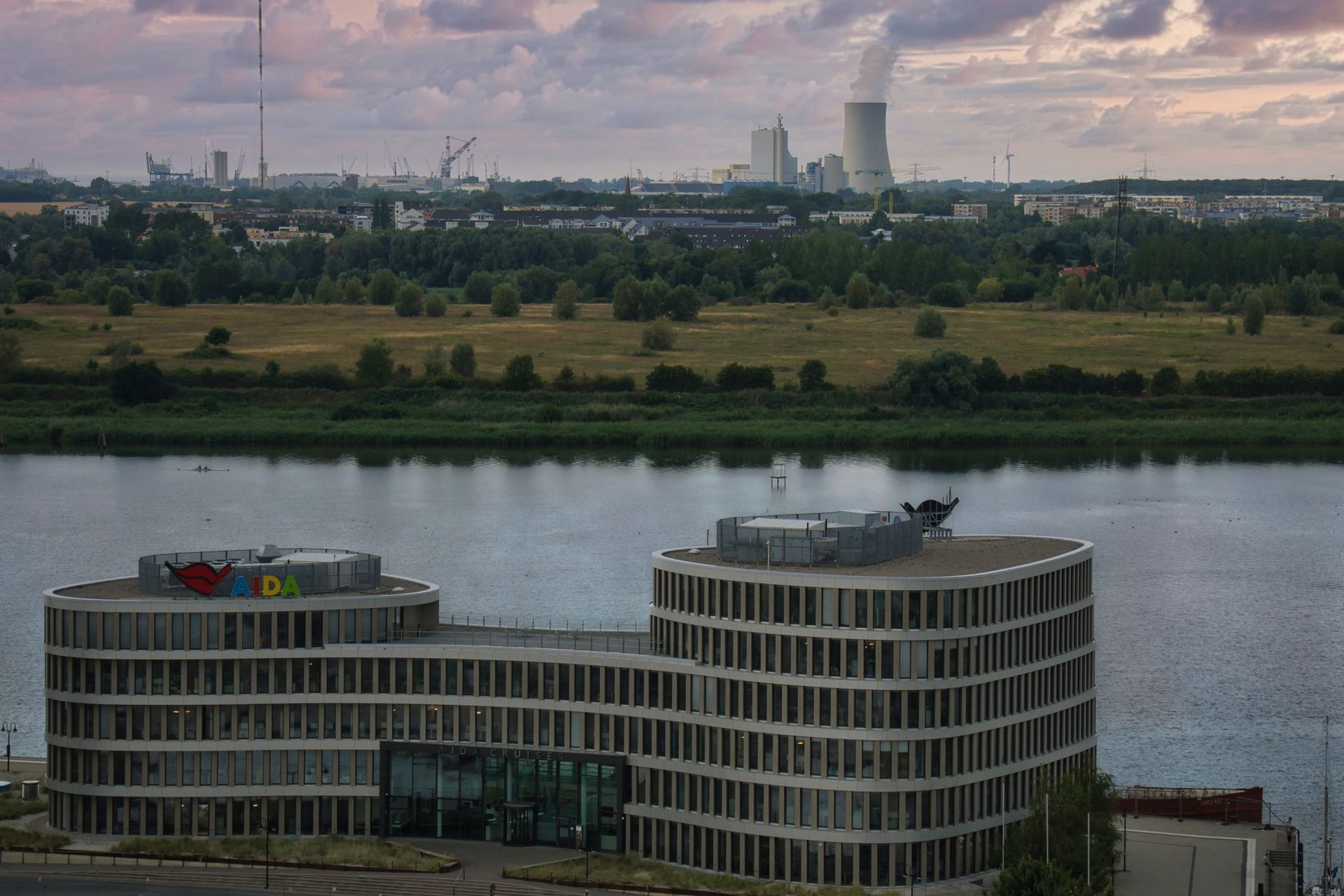 Aerial view of a modern office building beside a river in Rostock during sunset.