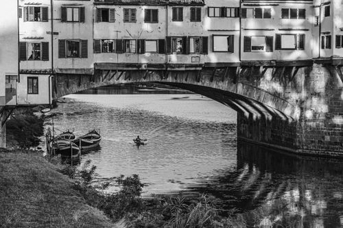 Free Monochrome image of Ponte Vecchio with boats and kayaker on the river. Stock Photo