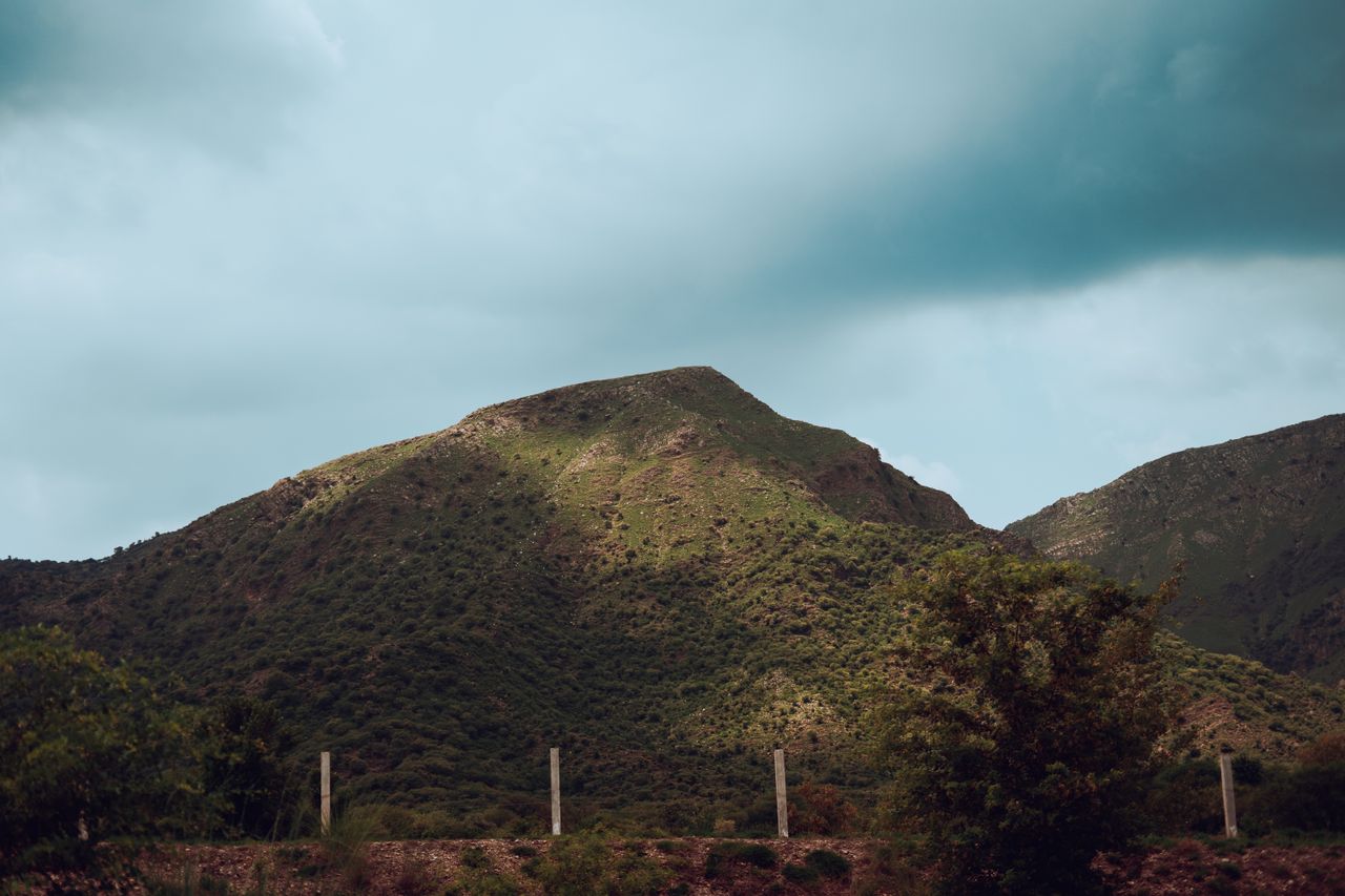 serene view of a lush green mountain with cloudy skies showcasing natu