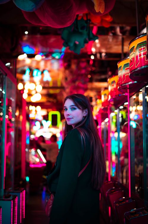 Free Adult woman standing in vibrant neon arcade in Namur, Belgium, creating a lively mood. Stock Photo