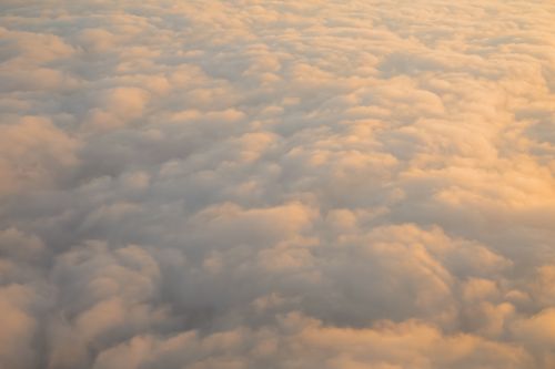Free A calming aerial shot of soft, fluffy clouds illuminated by the warm glow of sunset. Stock Photo