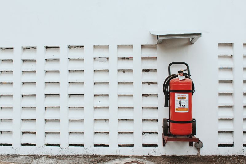 Red fire extinguisher mounted on a white wall