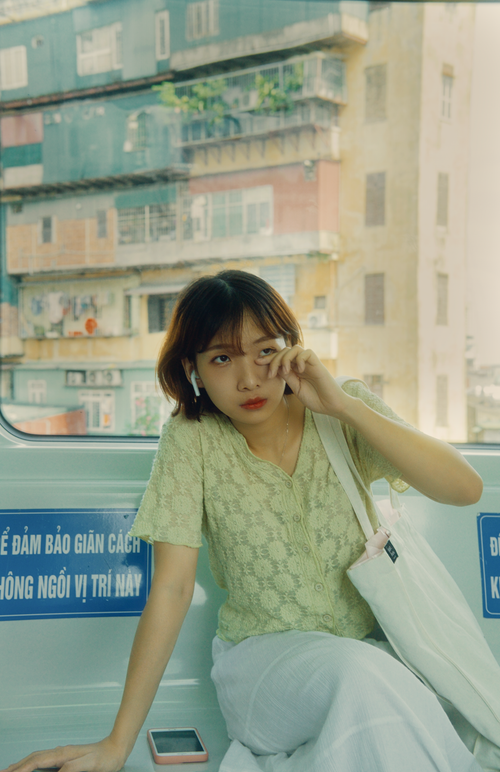 Free Woman in casual attire sitting inside a tram with a cityscape view through the window. Stock Photo