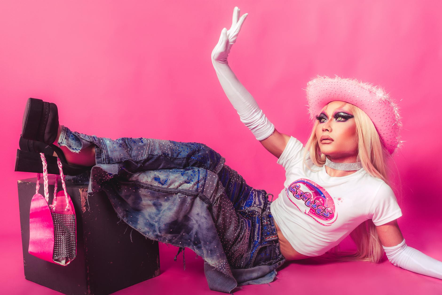 Fashionable model in Y2K style posing in a studio with vibrant pink background.