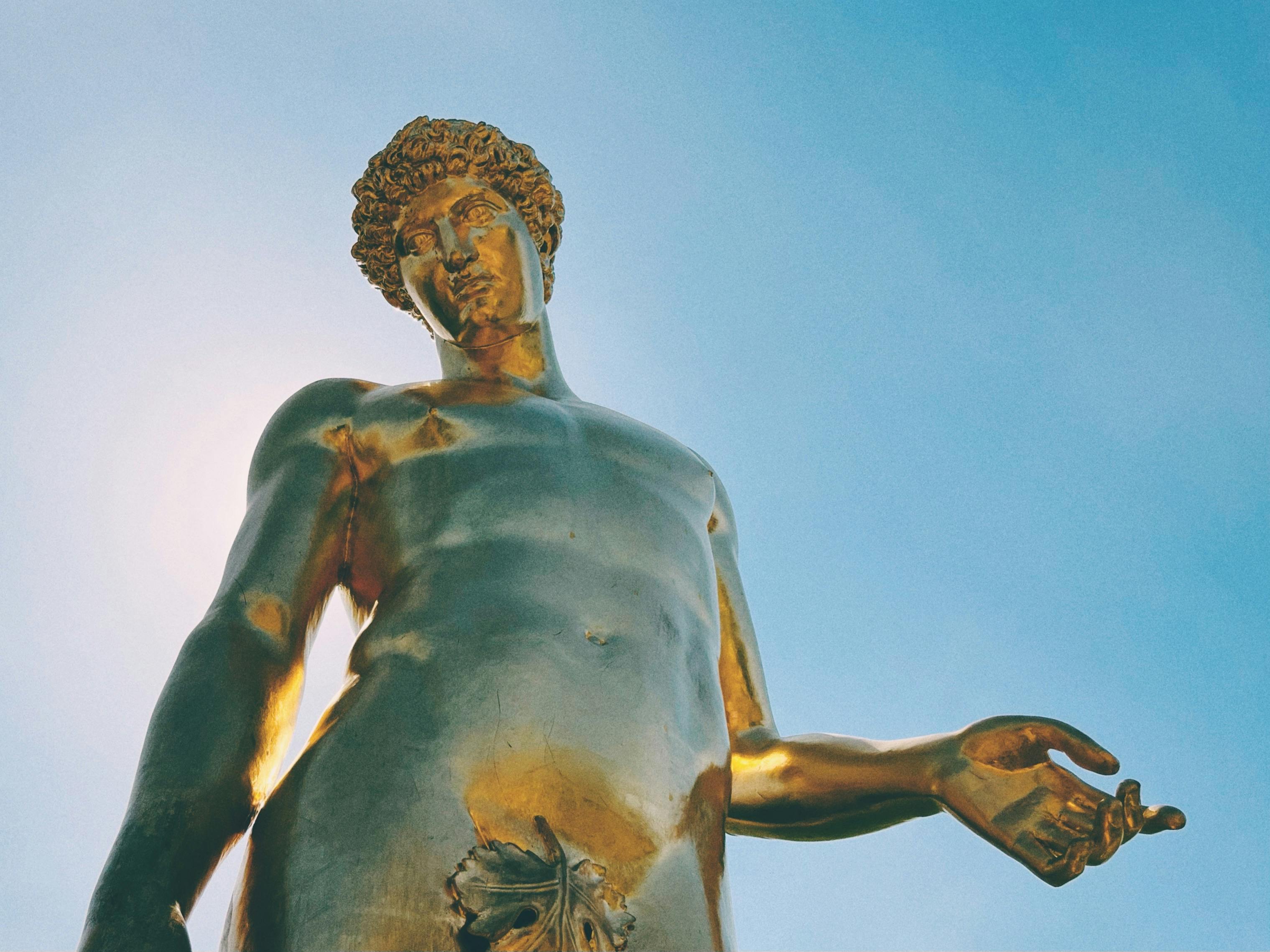 low angle shot of golden statue under blue sky