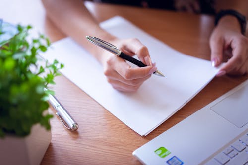 Person Holding a Pen and White Papers 