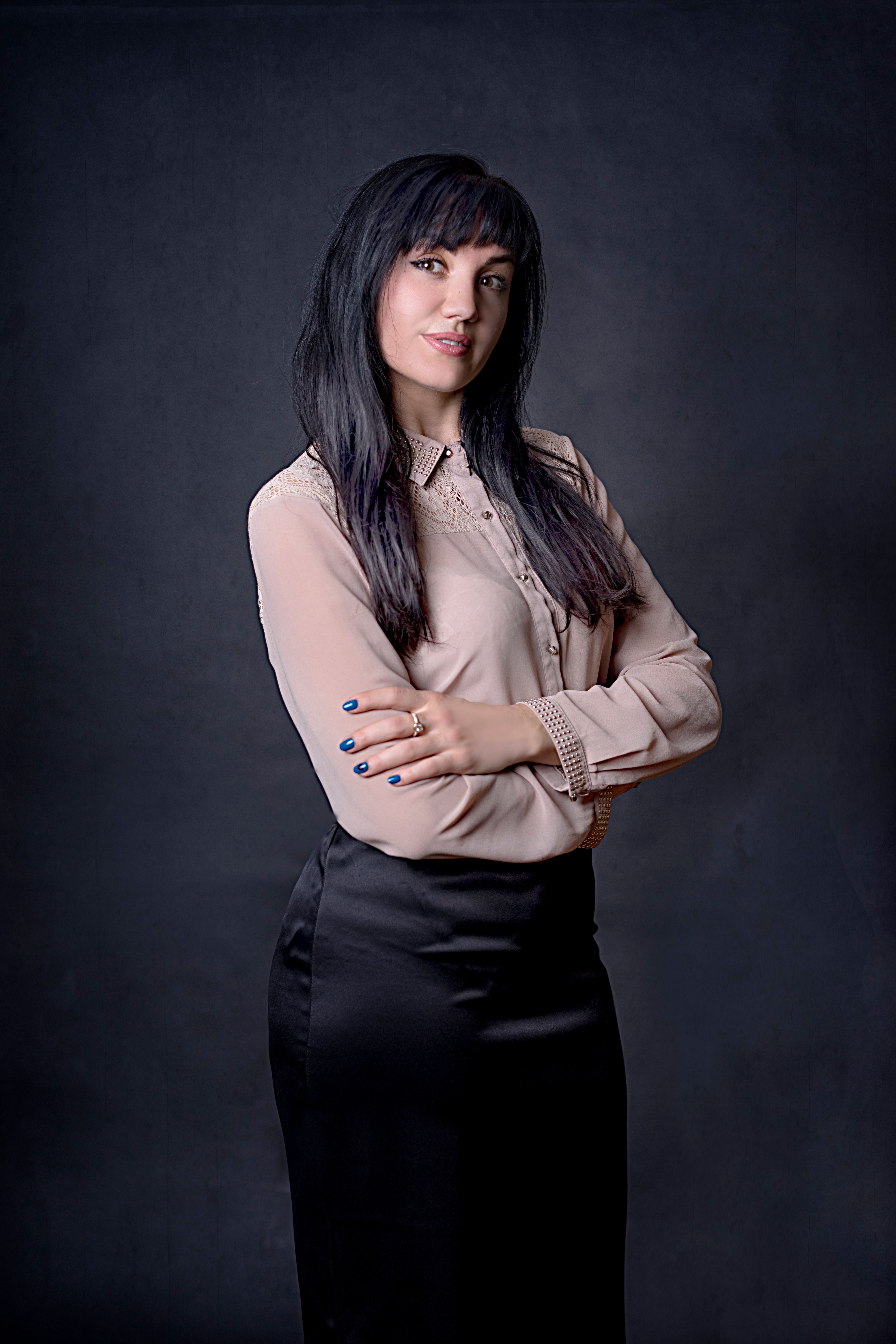 Studio portrait of a confident elegant woman in a black skirt and blouse.