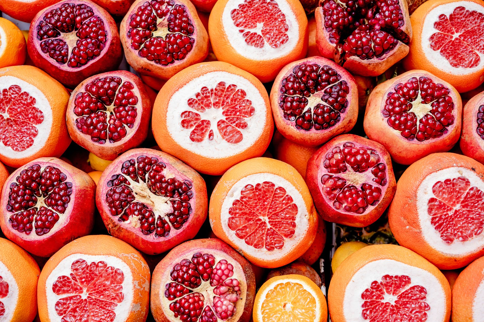 Hands scoring a pomegranate on a cutting board ready to be peeled