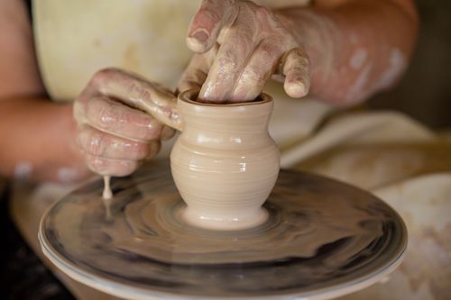 Free Hands crafting a clay vase on a pottery wheel in a close-up view, showcasing the art of pottery making. Stock Photo