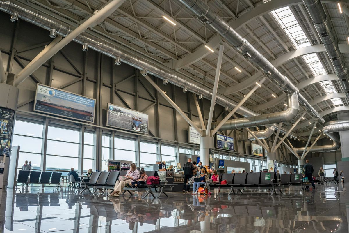 Spacious airport terminal interior with seated and walking passengers