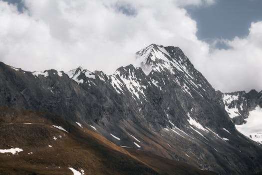 Soaring snow-capped peaks against cloudy skies in Tirol, Austria. Perfect for nature lovers.