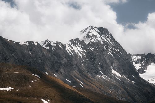 Free Soaring snow-capped peaks against cloudy skies in Tirol, Austria. Perfect for nature lovers. Stock Photo