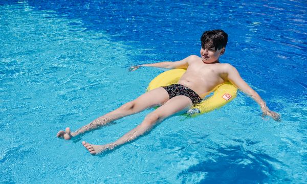 Child learning to float during first swim lesson