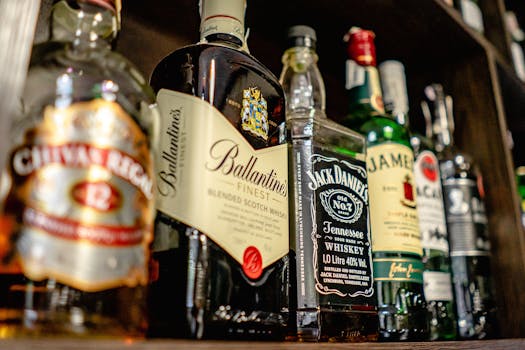 Close-up of various whiskey bottles on a bar shelf showcasing popular brands.