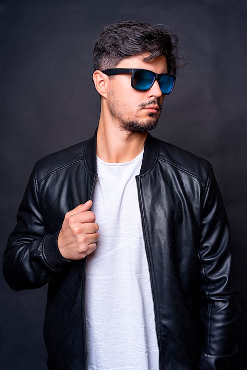 Free Close-Up Shot of a Man Wearing Black Leather Jacket and Sunglasses on Gray Background Stock Photo