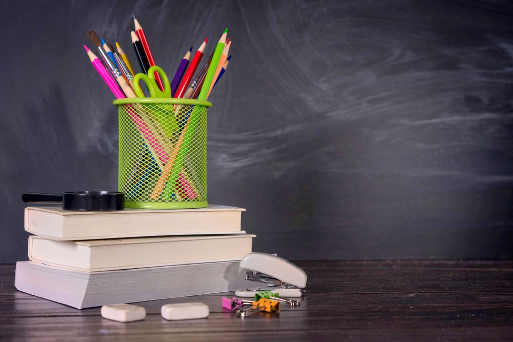 Pencils and school books in front of a blackboard