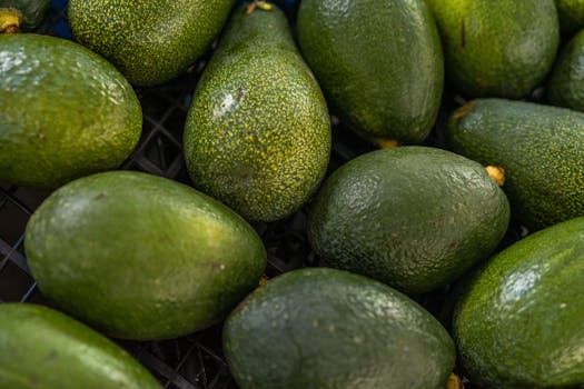A vibrant close-up of fresh avocados on display at a market, showcasing their rich green texture.