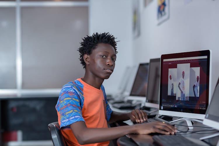 Boy Sitting At Desk Working At PC