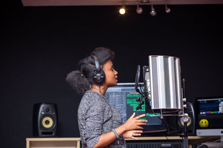 Woman In Headphone Recording Song In Studio