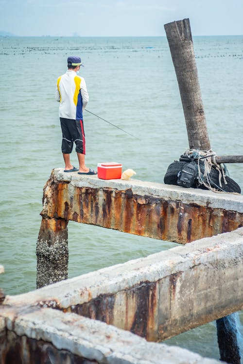 Free Man in White Shirt and Blue Shorts Standing on Dock Stock Photo