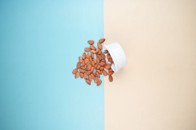 Natural whole almonds spilling from a bowl