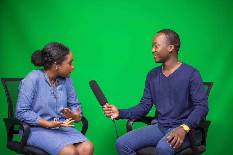 People With Microphone Filming Interview In Studio With Green Background