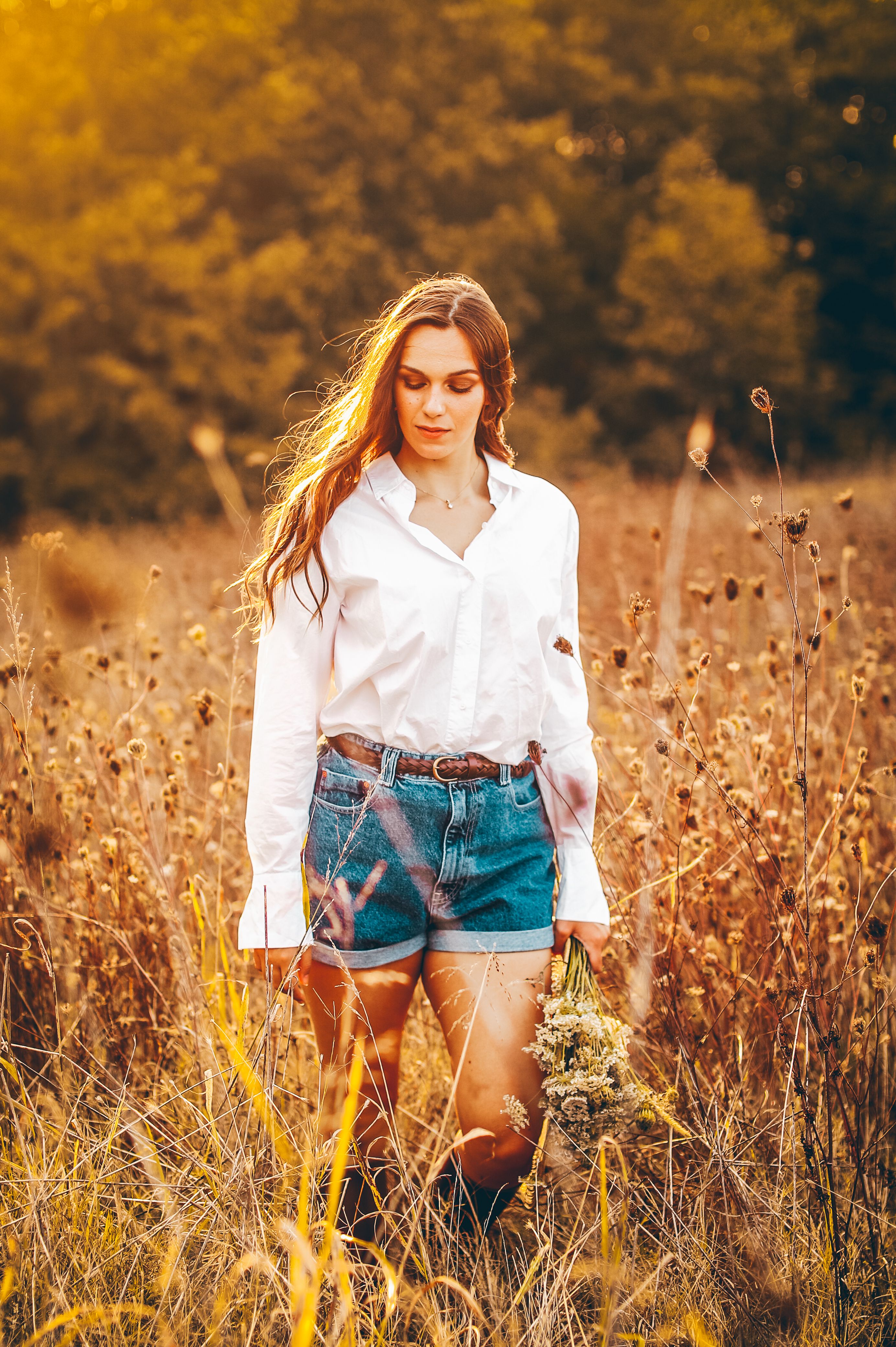 A Woman in a Grass Field Holding a Bunch of Flowers · Free Stock Photo