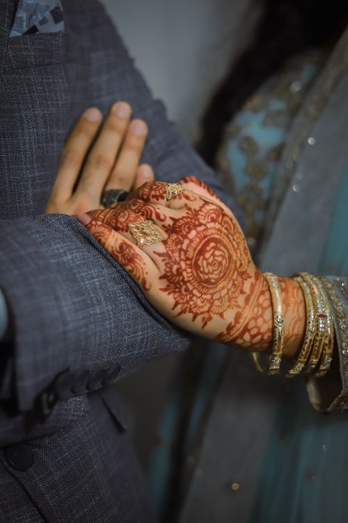 Free Close-up of a bride and groom's hands adorned with henna and gold jewelry, symbolizing love and tradition. Stock Photo