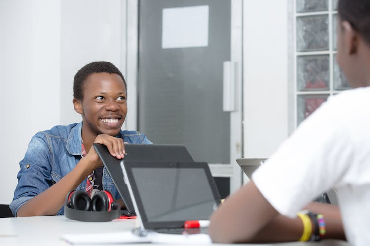 Smiling Men Working On Laptops In Office Talking 