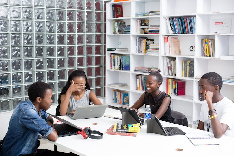 Group Of Teenagers Sitting With Laptops In A Library 