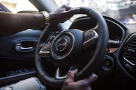 特写镜头中，一名男子的手放在豪华汽车方向盘上，突出了现代内饰