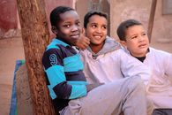 Three boys smiling and enjoying their time outdoors in Algeria, showcasing friendship and joy.