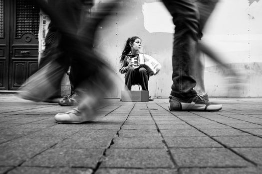 Grayscale Photo of a Girl Playing Musical Instrument on the Street Pants