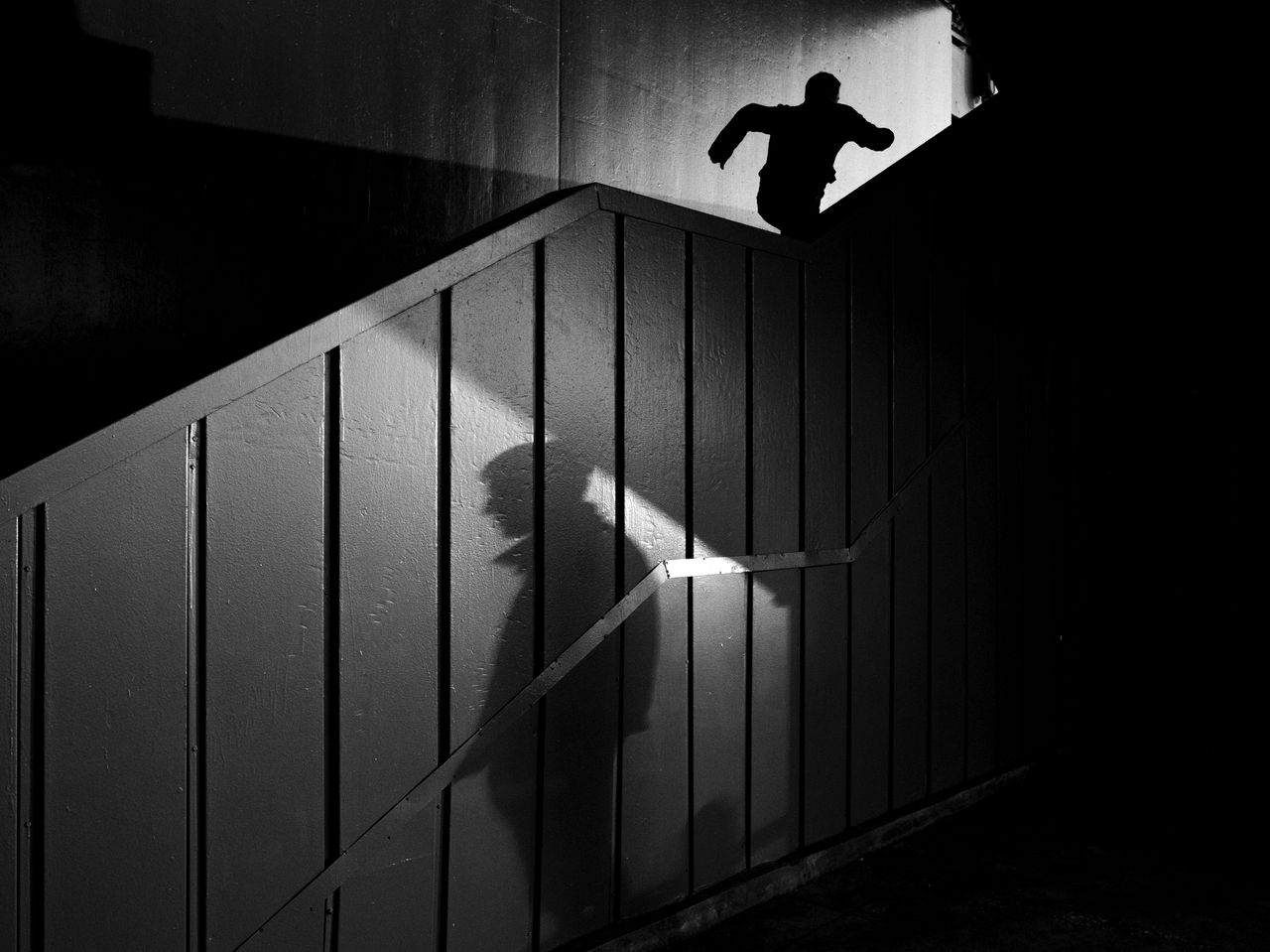 dynamic black and white silhouette of a man running upstairs with dram